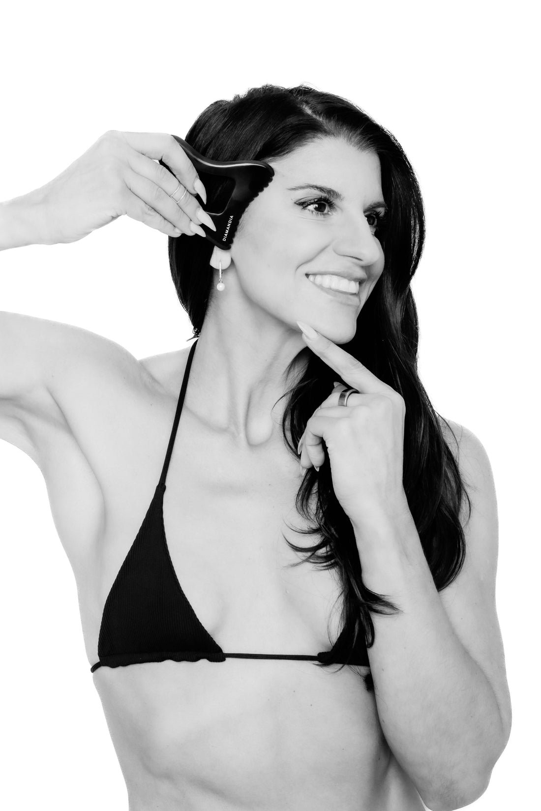A smiling woman holding her gua sha tool.